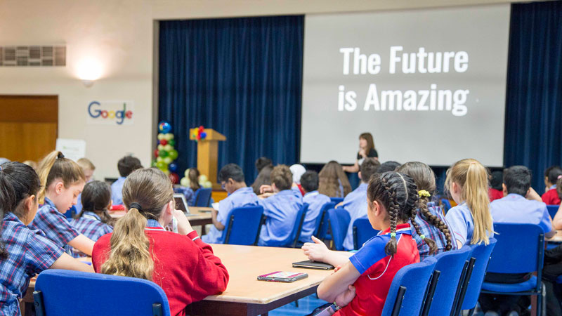 students sat at tables in hall, while watching a presentations that reads 'The Future is Amazing'