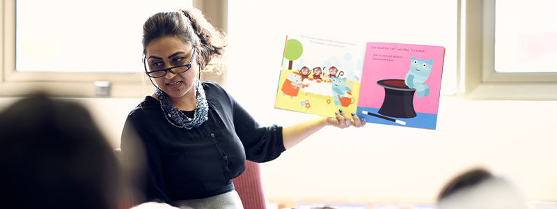 Teacher reading a picture book to a group of children