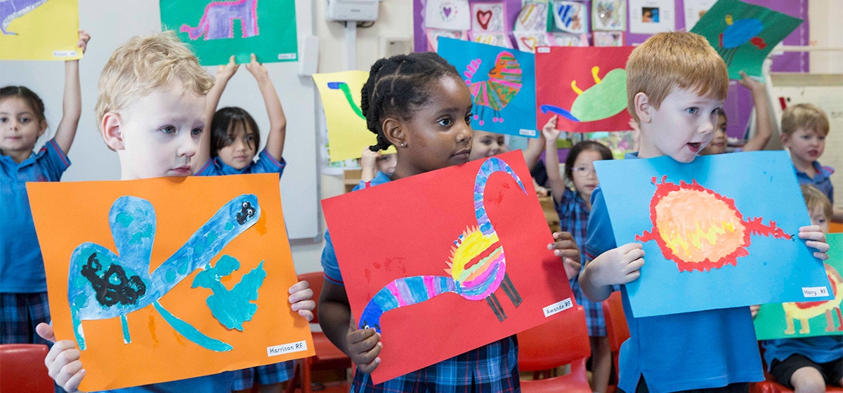 Reception children holding up artwork